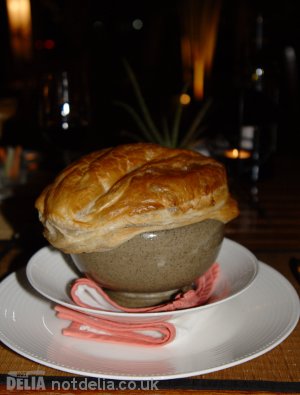 A very large bowl of French onion soup with a big pastry lid